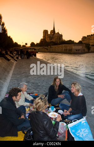 I parigini il pic-nic lungo il Fiume Senna al tramonto a Parigi, Francia. Foto Stock