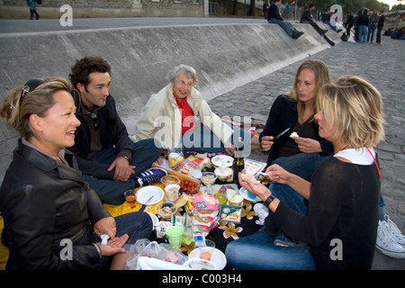 I parigini il pic-nic lungo il Fiume Senna al tramonto a Parigi, Francia. Foto Stock