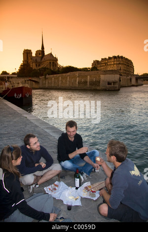 I parigini il pic-nic lungo il Fiume Senna al tramonto a Parigi, Francia. Foto Stock