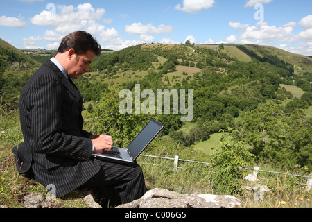 Uomo d'affari che lavorano al di fuori con la banda larga mobile e il computer portatile Foto Stock