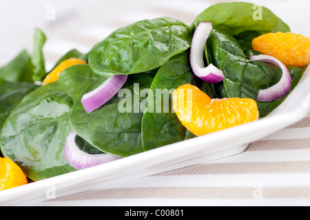 Spinaci freschi con mandarini arance, le cipolle rosse e una luce miele di arancio medicazione. Foto Stock