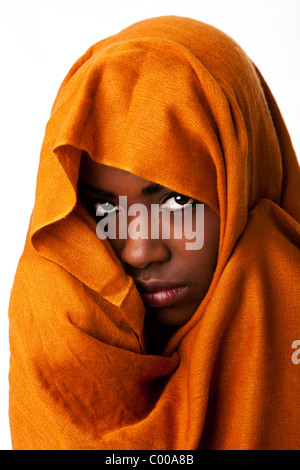 Bella misteriosa africana beduini nomadi volto femminile in terra ocra testa tono wrap sciarpa cercando. Foto Stock