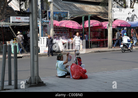 Vecchio mercante seduto sulla strada di Bangkok Foto Stock