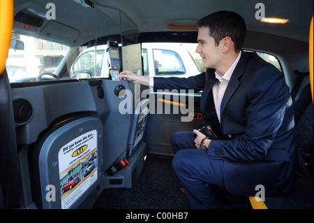 Un uomo di pagare per un taxi con un installato di recente macchina Verifone che prende i pagamenti da carte di credito o debito Foto Stock