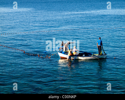 I pescatori costieri in imbarcazioni a remi tirando le estremità di una sciabica net off una vacanza in spiaggia Playa Blanca Lanzarote Foto Stock