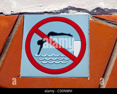 Una piastrella ceramica segno di avvertimento contro le immersioni in acque poco profonde in una vacanza hotel piscina Playa Blanca Lanzarote Foto Stock