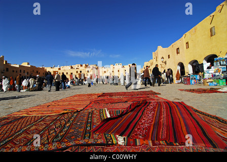 Algeria, Ghardaia, persone al marketplace con varietà di tappeti esposti per la vendita in primo piano Foto Stock