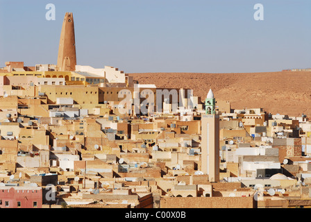 Algeria, Ghardaia, vista città con mattoni di fango e di abitazione minareto alto contro il cielo chiaro Foto Stock