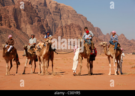I turisti a cavallo di cammelli nel deserto, Wadi Rum, Giordania. Foto Stock