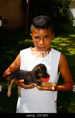 Ragazzo tenendo un cucciolo nelle sue braccia, Fortaleza Ceará, Brasile, Sud America Foto Stock