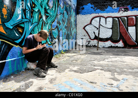 Dieci-anno-vecchio ragazzo giocando con il suo Nintendo di fronte a un muro di graffiti, Germania, Europa Foto Stock