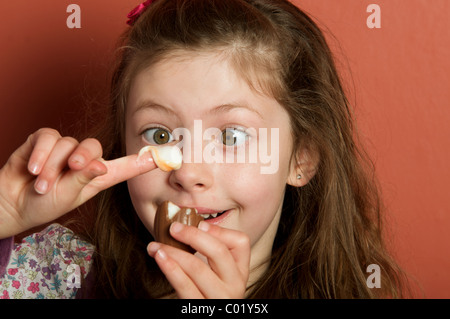 Ragazza giovane mangiare un Cadbury crema di uovo Foto Stock