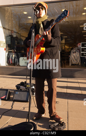 Un suonatore ambulante a suonare la chitarra in Norwich , Norfolk , Inghilterra , Inghilterra , Regno Unito Foto Stock