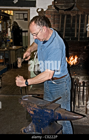 Usando un attrezzo appuntito per effettuare fori dei chiodi in ferro di cavallo Foto Stock