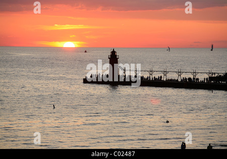 Tramonto sul lago Michigan con il faro e il molo sud in Sud Haven Michigan in una serata estiva Foto Stock