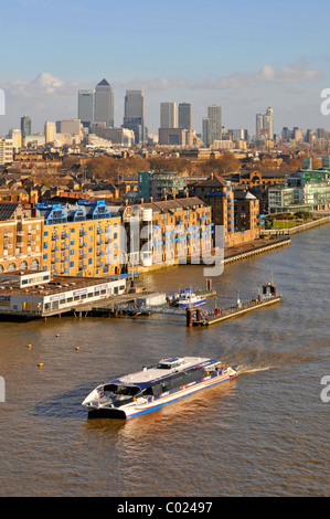 Autobus acquatico Thames Clipper nel paesaggio urbano di Tower Hamlets e piscina di Londra con appartamenti lungo il fiume e lo skyline di Canary Wharf oltre l'Inghilterra UK Foto Stock