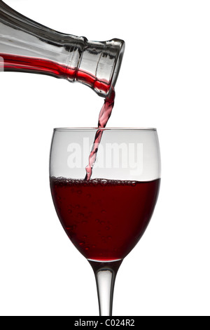 Vino rosso colare giù da un decanter vino in un bicchiere di vino su sfondo bianco Foto Stock