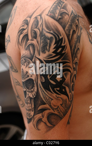 La parte superiore del braccio di un giovane uomo appena tatuato con un cranio Foto Stock
