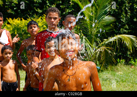 Ragazzi la spruzzatura tra loro con un tubo flessibile di acqua, Fortaleza Ceará, Brasile, Sud America Foto Stock