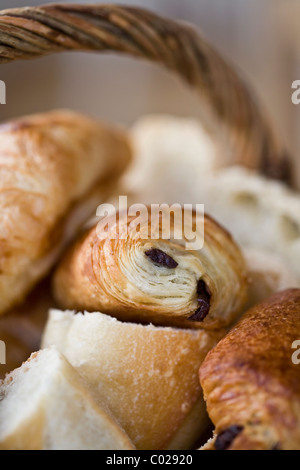 Croissant freschi e pane in un tradizionale cesto in vimini serviti per colazione in Bretagna, Francia Foto Stock