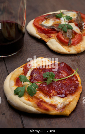 Pizzette, pizzette con mozzarella di bufala, il Chorizo e il coriandolo, anteriore e i pomodori e le acciughe, posteriore Foto Stock