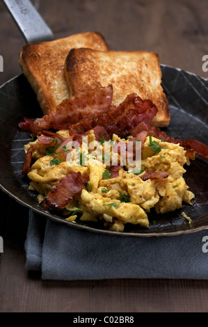 Uova strapazzate con pancetta fritta e toast Foto Stock