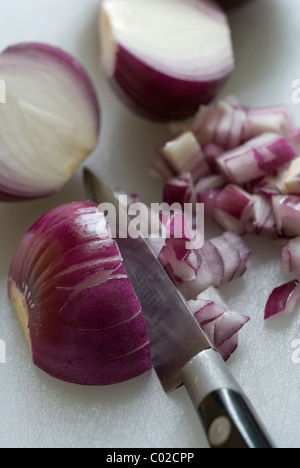 Tritare le cipolle rosse su un bianco tagliere. Foto Stock