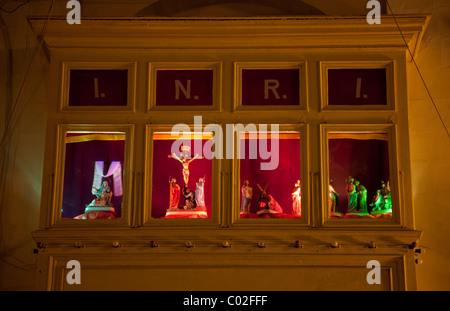 Molte famiglie a Gozo (Malta) impostare visualizza delle statue cattolica dietro windows per i passanti da vedere durante la Settimana Santa. Foto Stock