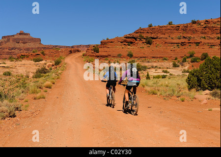 Due ciclisti che viaggiano su una pista polverosa nel Parco Nazionale di Canyonlands, Island in the Sky, White Rim Trail, Utah, Stati Uniti d'America Foto Stock