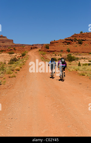 Due ciclisti che viaggiano su una pista polverosa nel Parco Nazionale di Canyonlands, Island in the Sky, White Rim Trail, Utah, Stati Uniti d'America Foto Stock