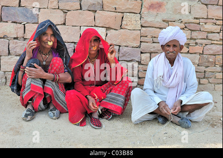 Due donne indiane con golden naso-ring e un anziano Indian testa di uomo con turbante seduto in abbigliamento tradizionale sul pavimento Foto Stock