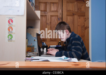 Un modello rilasciato la foto di un ragazzo di undici anni facendo i compiti sul suo computer portatile nella sua camera da letto Foto Stock