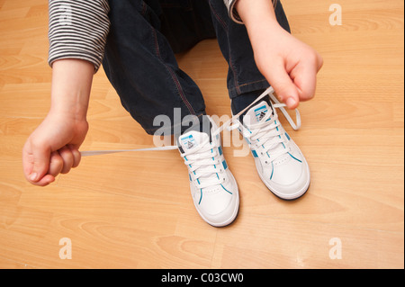 Un modello rilasciato foto di un 7 anno vecchio ragazzo imparare a legare il suo lacci delle scarpe nel Regno Unito Foto Stock