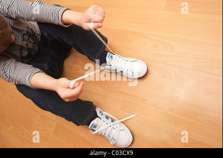 Un modello rilasciato foto di un 7 anno vecchio ragazzo imparare a legare il suo lacci delle scarpe nel Regno Unito Foto Stock