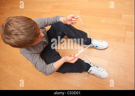 Un modello rilasciato foto di un 7 anno vecchio ragazzo imparare a legare il suo lacci delle scarpe nel Regno Unito Foto Stock