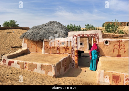 Una donna velata in un sari permanente al dipinto di ingresso al suo cortile, il Deserto di Thar, Rajasthan, Nord India, India, Asia Foto Stock