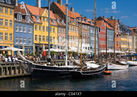Una folla di persone mangiare il pranzo presso i ristoranti lungo Nyhavn o un nuovo canale del porto di Copenhagen, Danimarca. Foto Stock
