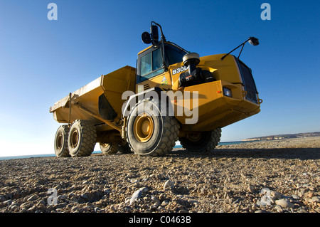 Una campana B30D Caterpillar Dumper su Seaford beach, East Sussex, aiutando a combattere l'erosione ripristinando i livelli di ghiaia. Foto Stock