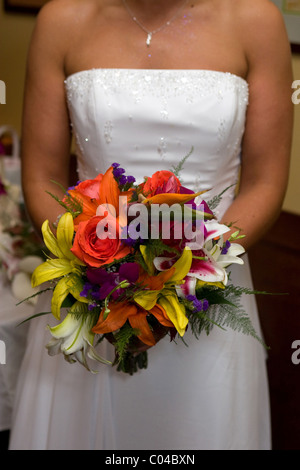 Una sposa in bianco di un abito da sposa mantiene il suo bouquet nuziale. Foto Stock