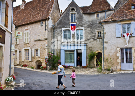 Donna che trasportano baguette francese grissino passeggiate con il bambino ad angoli sur l'Anglin, Vienne, Poitou-Charantes, Francia Foto Stock