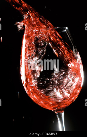 Vino rosso schizzi violentemente in un bicchiere con molti direttori della fotografia Foto Stock