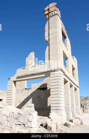 I resti del cuoco Bank Building, con l'Arcobaleno montagne sullo sfondo, in riolite, Nevada. Foto Stock