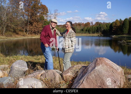 Coppia senior in piedi da un lago in autunno. Foto Stock