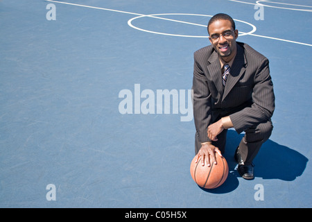 Un giovane uomo in un business suit in posa il vuoto di pallacanestro con un sacco di copyspace. Foto Stock