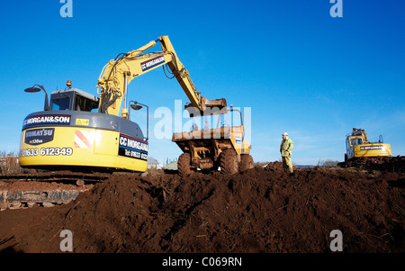 Meccanica escavatrice scavo a terra su un sito di costruzione. Foto Stock