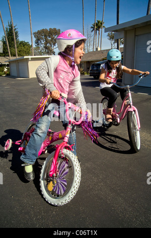 Una bambina di cinque anni impara a guidare la sua nuova bicicletta in una cassetta di sicurezza parcheggio in Laguna Niguel, CA. Foto Stock