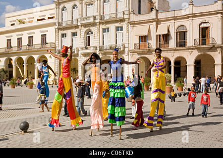 Un gruppo di artisti di strada o gli artisti interpreti o esecutori in passerella su palafitte a piedi attraverso le strade di La Habana, Cuba in luminosi colorati costumi Foto Stock