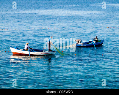 I pescatori costieri in imbarcazioni a remi tirando le estremità di una sciabica net off una vacanza in spiaggia Playa Blanca Lanzarote Foto Stock