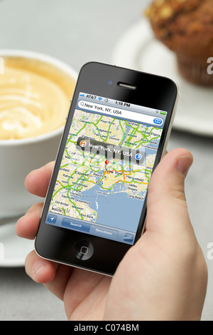 Uomo che mostra New York City map con Google map applicazione sul suo iPhone 4 mentre godendo il suo caffè Foto Stock