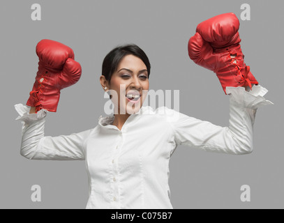 Imprenditrice in guantoni da pugilato tifo con le braccia sollevate Foto Stock